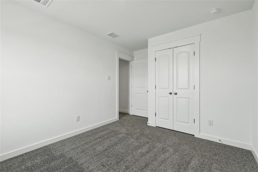 Unfurnished bedroom with dark carpet and a closet Unfurnished bedroom with dark carpet and a closet