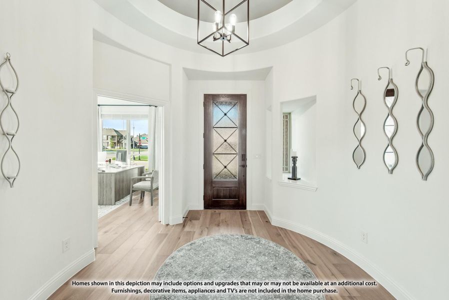 Bright home entryway with dark wood front door, tray ceiling, pendant light, and light hardwood floors