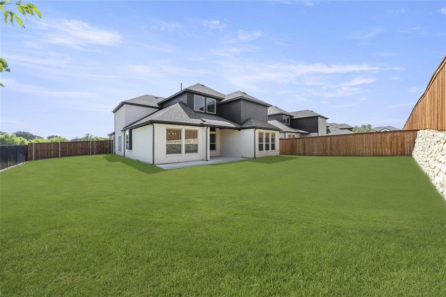 Expansive green lawn with a newly constructed privacy fence, featuring a stone retaining wall Expansive green lawn with a newly constructed privacy fence, featuring a stone retaining wall