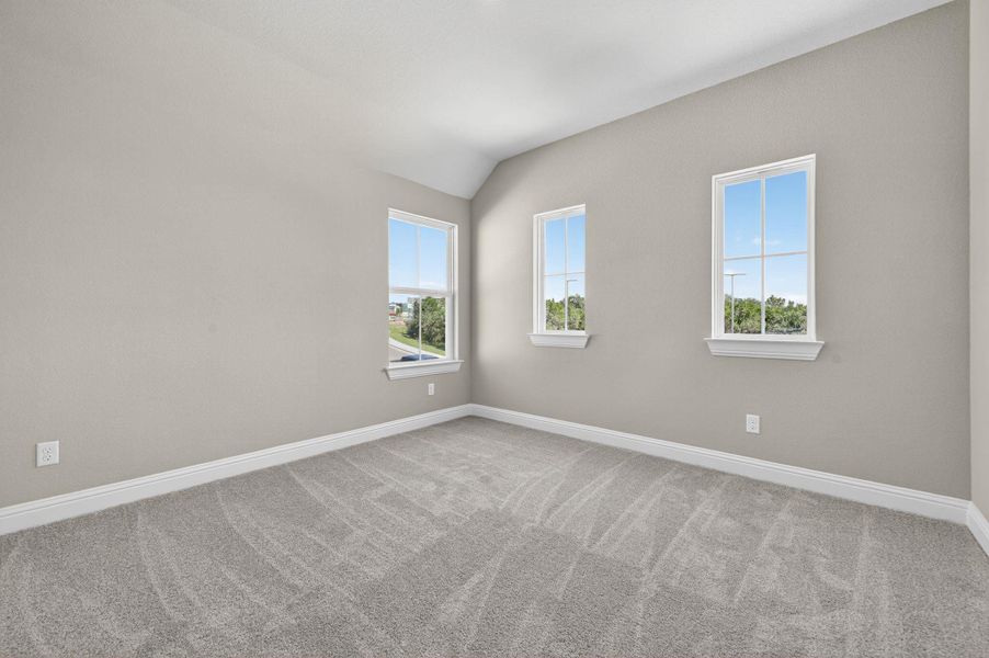 Empty room featuring light carpet and vaulted ceiling