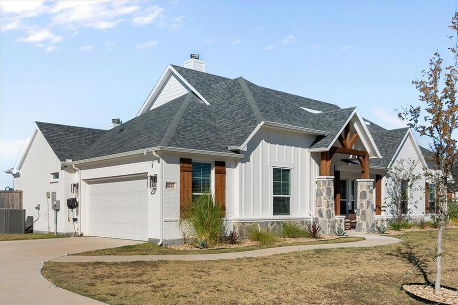 View of front of property featuring a chimney, driveway, a garage, and roof with shingles