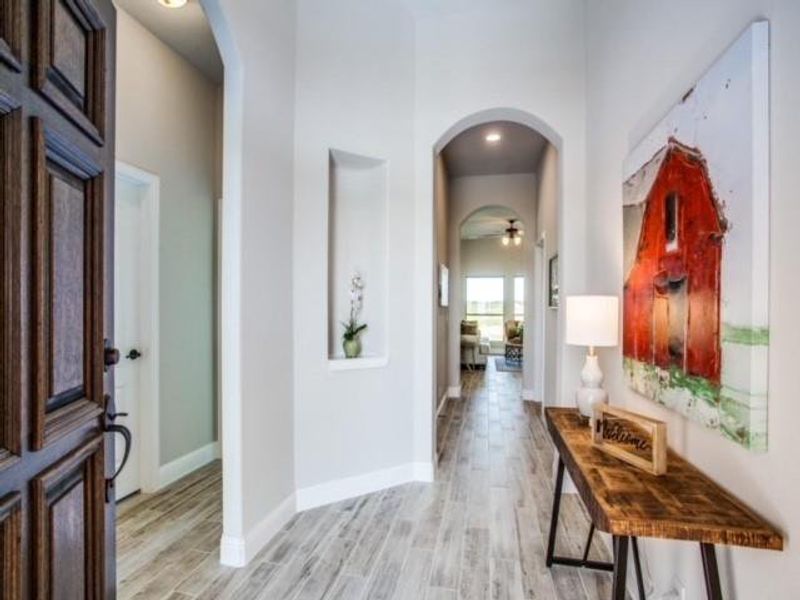 Hallway with arched walkways, light wood-style floors, and recessed lighting