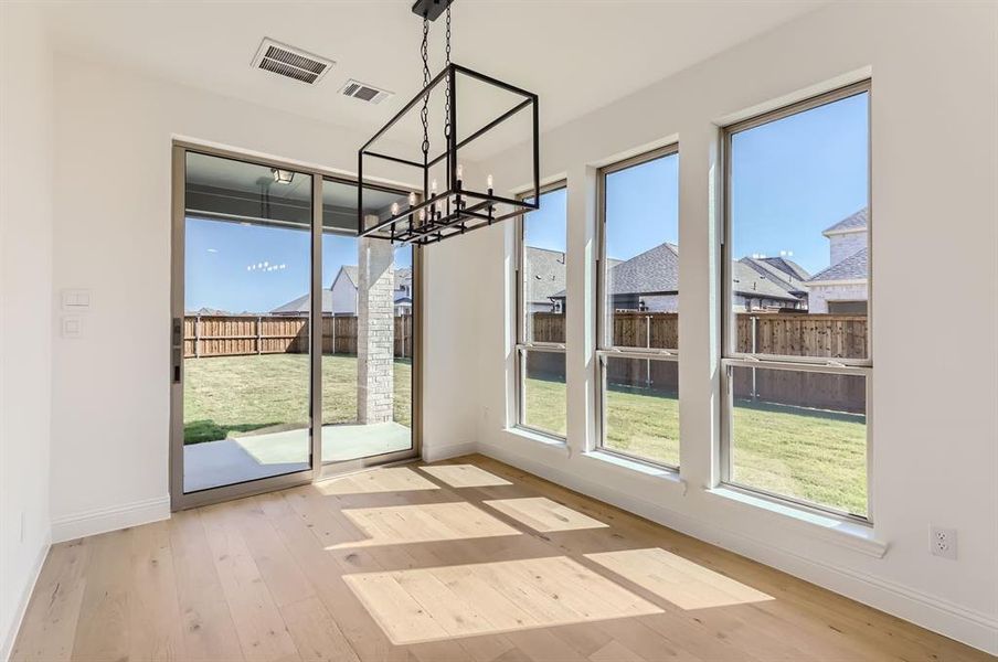 Unfurnished dining area featuring light wood-type flooring, a notable chandelier, and plenty of natural light