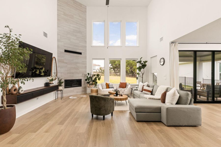 Vaulted living space featuring a floor-to-ceiling fireplace with a modern linear insert, wood-finish flooring, and multiple large windows