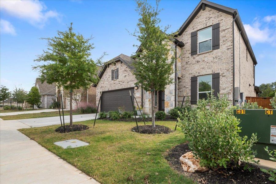 View of front of home featuring a front yard, concrete driveway, brick siding, and a garage