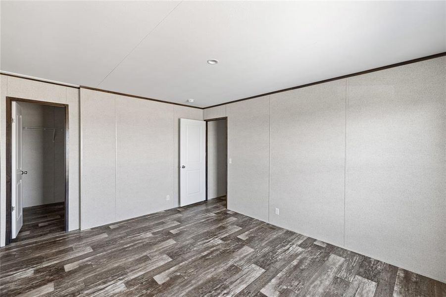 Unfurnished bedroom featuring crown molding and dark wood-type flooring