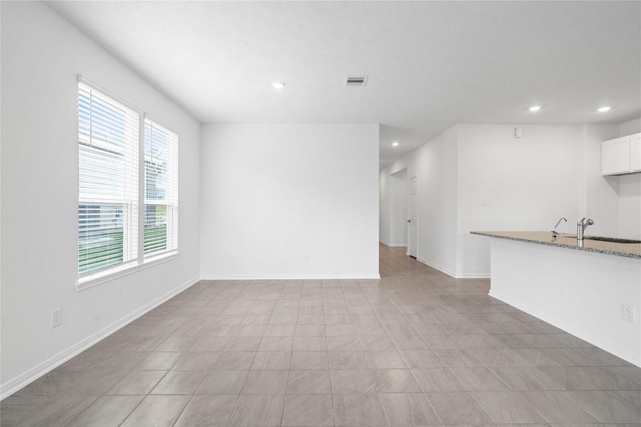 Start your day with a warm cup of coffee and quality time in this charming dining area! Highlights include large windows with blinds, custom neutral paint, tile flooring, and high ceilings with recessed lighting.