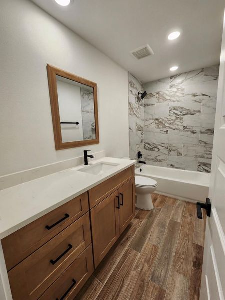 Bathroom featuring dark wood-style floors, vanity, bathtub / shower combination, and recessed lighting