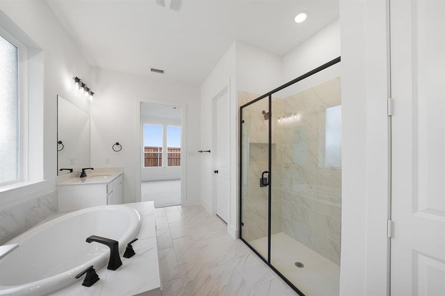 Full bath featuring light marble finish floors, a garden tub, a marble finish shower, and vanity