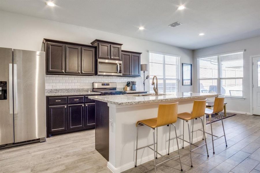 Kitchen with visible vents, a breakfast bar, decorative backsplash, stainless steel appliances, and a sink