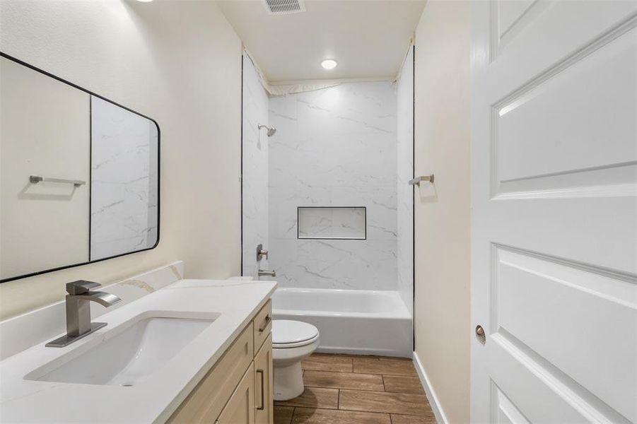 Modern bathroom featuring a single vanity with light wood cabinetry, a white countertop, and a rectangular undermount sink Modern bathroom featuring a single vanity with light wood cabinetry, a white countertop, and a rectangular undermount sink