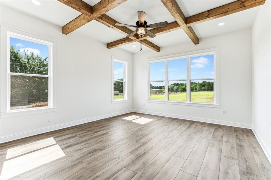 Primary bedroom with cross beam ceiling, light hardwood / wood-style flooring, and ceiling fan