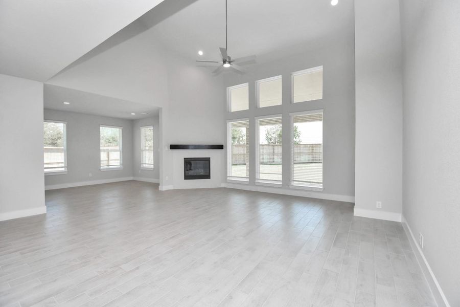 Relax and unwind in this inviting family room, illuminated by abundant natural light streaming in through tall windows, complemented by high ceilings and stunning flooring. Stay comfortable year-round with the gentle breeze from the ceiling fan, creating the perfect atmosphere for family gatherings. Sample photo of completed home with similar floor plan. Actual colors and selections may vary.