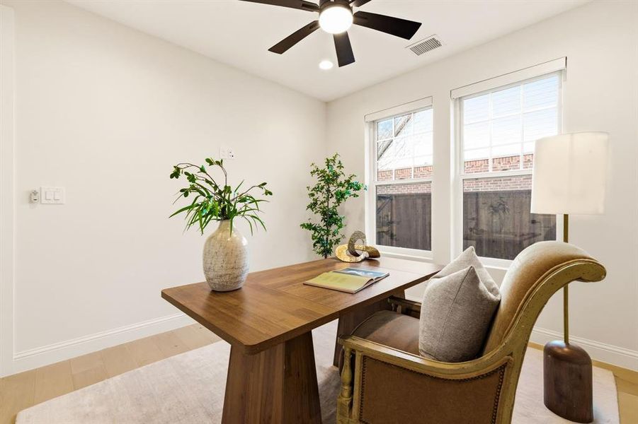Office area with a ceiling fan and light wood finished floors