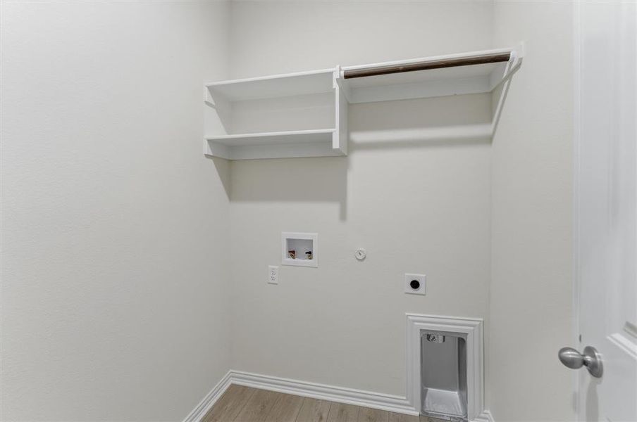 Dedicated laundry area featuring a light wood-finish floor, white baseboards, and built-in white shelving