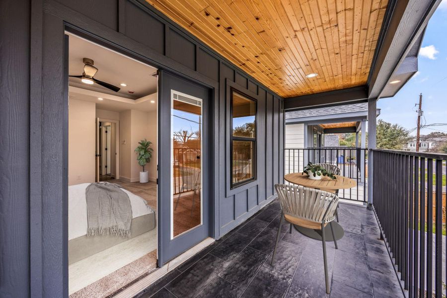 Private covered balcony accessible from the primary bedroom, featuring a wood-paneled ceiling, recessed lighting, and space for outdoor seating. Perfect for morning coffee or relaxing evenings while enjoying fresh air and neighborhood views.