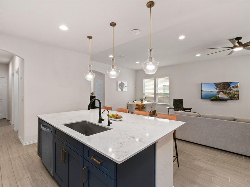 Kitchen with light stone counters, arched walkways, pendant lighting, wood tiled finished floors, and open floor plan