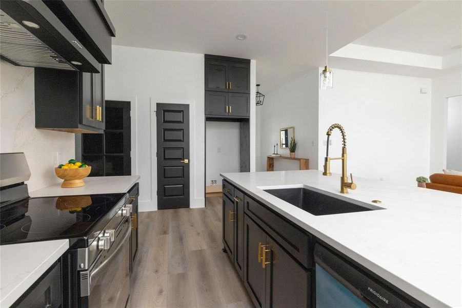 Kitchen with dishwasher, hanging light fixtures, sink, stainless steel stove, and range hood