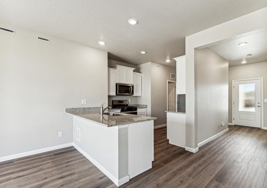 The kitchen has stainless steel appliances and plank flooring.