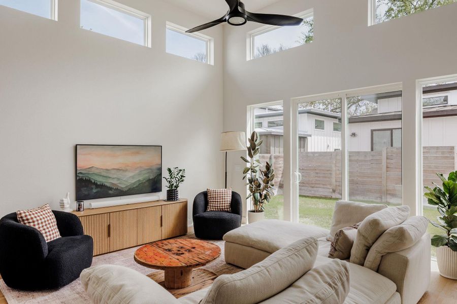 Living area with ceiling fan, a high ceiling, and wood finished floors
