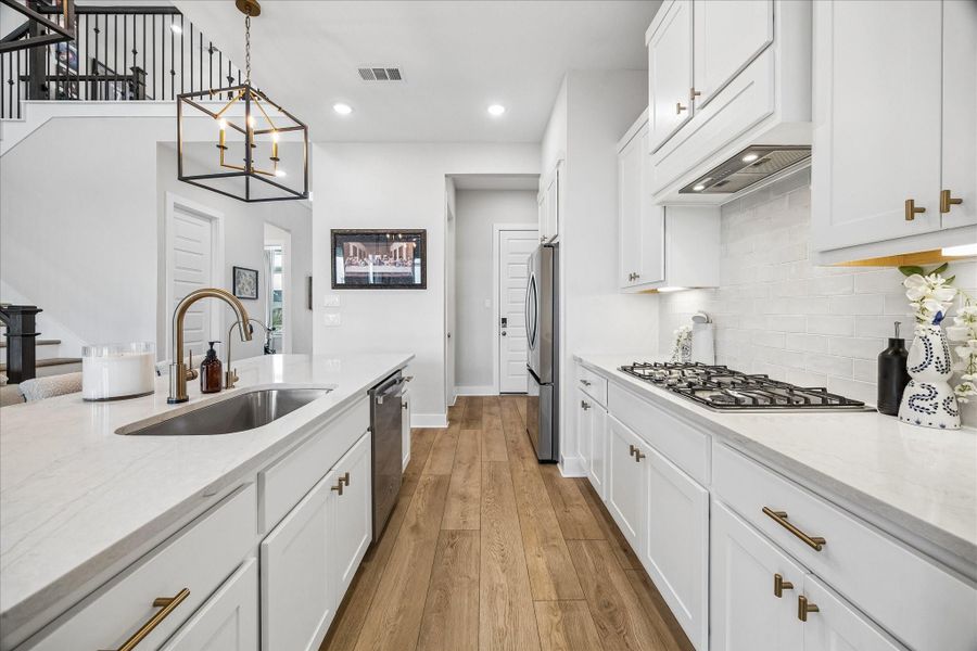 A bright and cohesive kitchen showcases white countertops, backsplash, and cabinetry, creating a clean and timeless aesthetic.