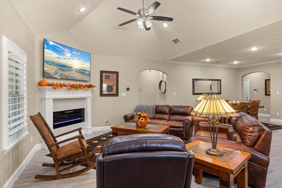 Living area featuring arched walkways, recessed lighting, ceiling fan, a glass covered fireplace, and vaulted ceiling Living area featuring arched walkways, recessed lighting, ceiling fan, a glass covered fireplace, and vaulted ceiling