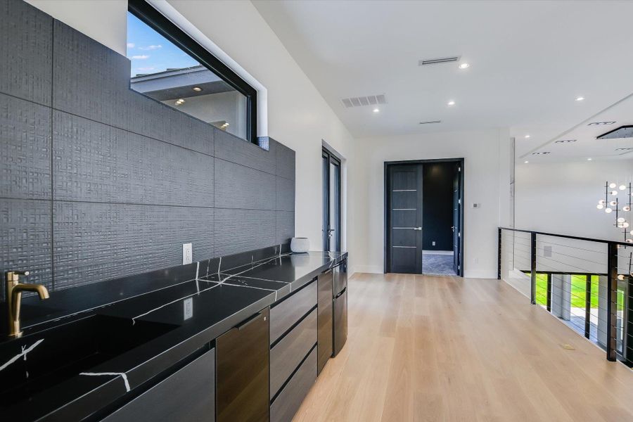 sink and serving area upstairs near media room with modern cabinets, dark countertops, plenty of natural light, and light wood-style flooring sink and serving area upstairs near media room with modern cabinets, dark countertops, plenty of natural light, and light wood-style flooring