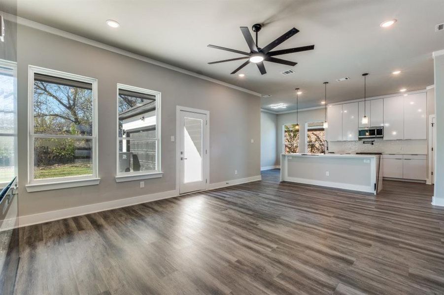 Unfurnished living room with ceiling fan, dark wood-style flooring, ornamental molding, and recessed lighting
