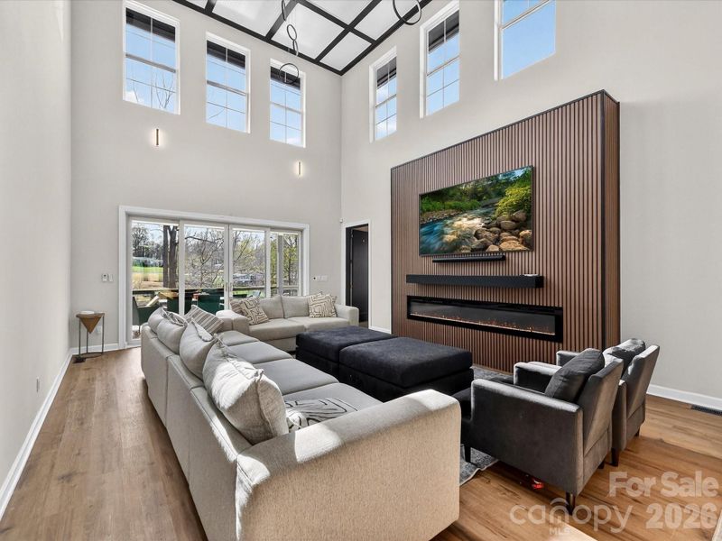 Bright, open-concept family room with soaring ceilings, a statement fireplace wall, and seamless flow into the kitchen and dining areas.