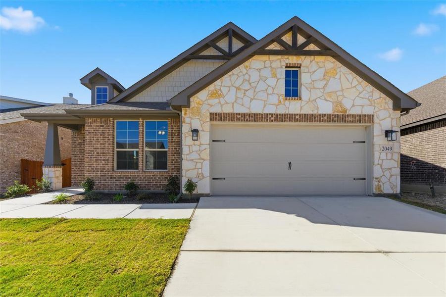 View of front of property with stone siding, concrete driveway, a front yard, and a garage