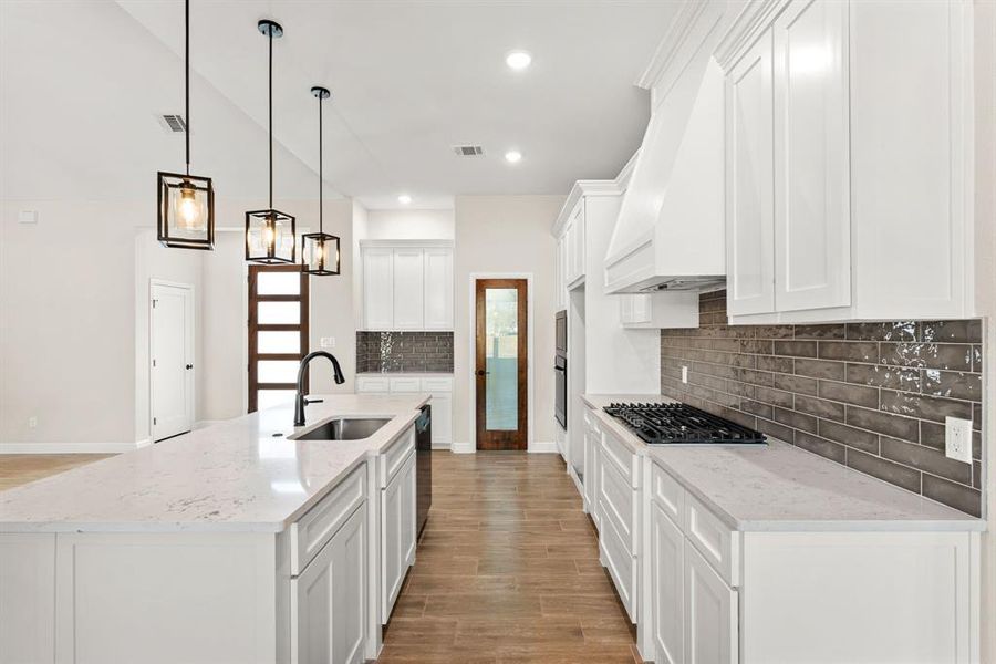 Kitchen featuring wood finish floors, light stone counters, white cabinetry, a kitchen island with sink, and recessed lighting