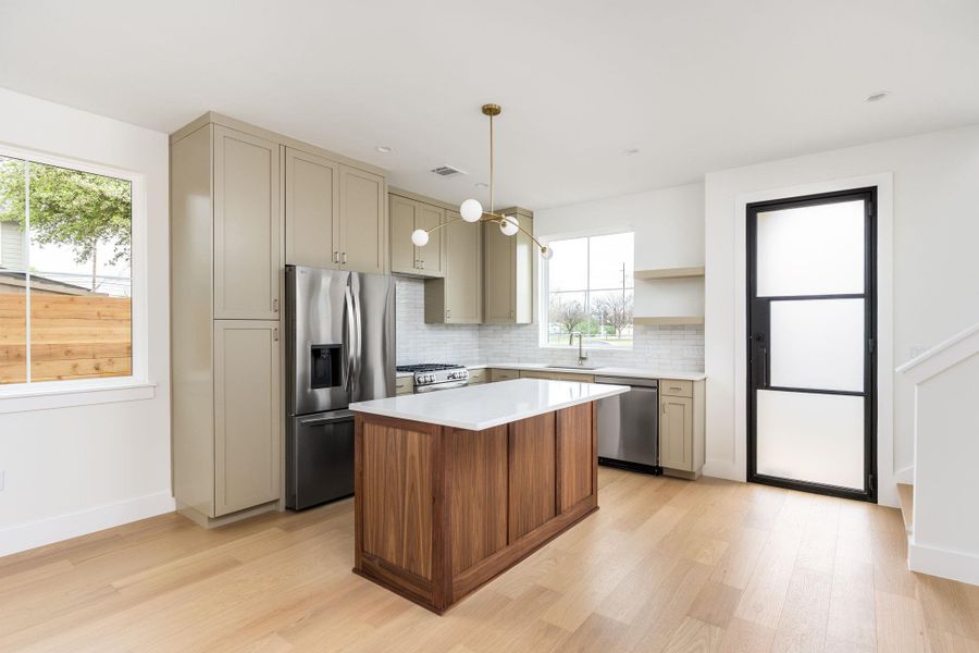 Kitchen featuring stainless steel appliances, decorative backsplash, a center island, and light wood-type flooring