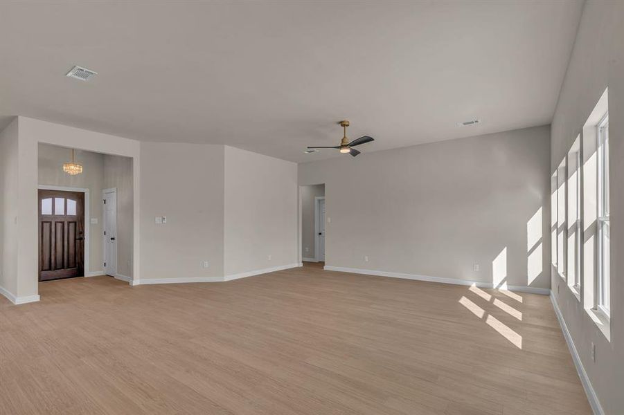 Spare room with ceiling fan with notable chandelier and light hardwood / wood-style flooring