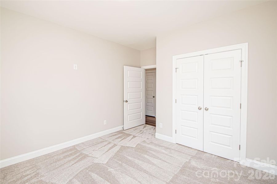 Bedroom #3 features plush carpet, a spacious closet, a large window, and an added outlet for easy ceiling fan installation.