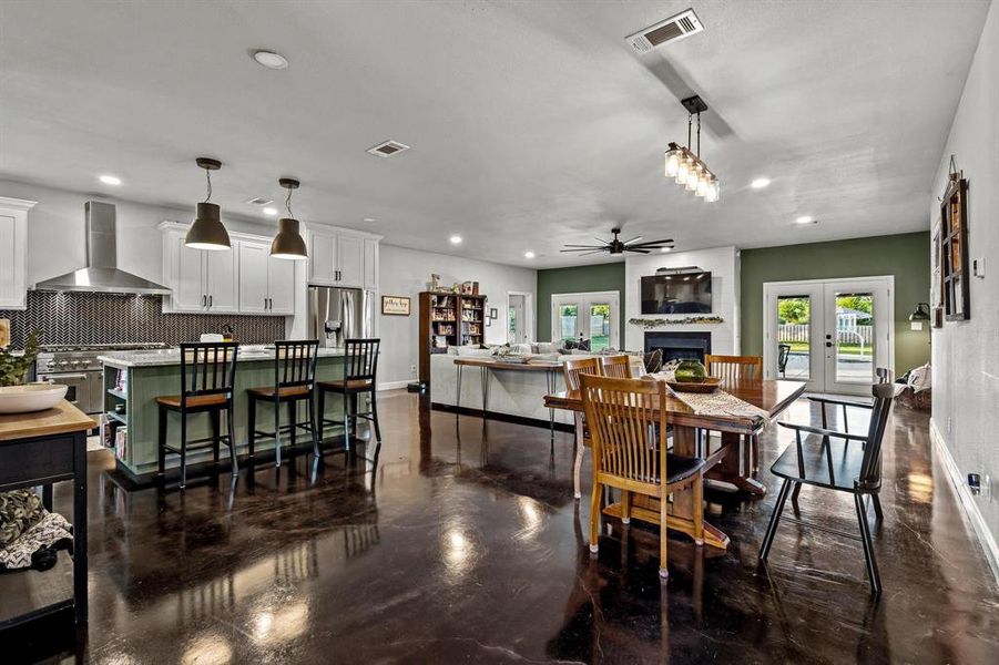 Dining area featuring a fireplace, french doors, recessed lighting, and concrete flooring Dining area featuring a fireplace, french doors, recessed lighting, and concrete flooring