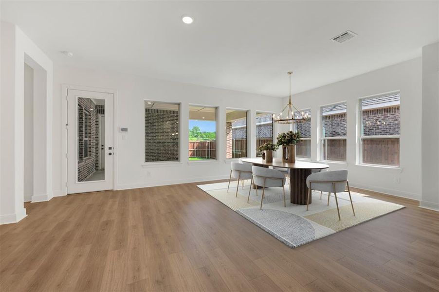 Spacious dining area featuring wood-finish flooring, ample natural light from multiple windows, and recessed lighting Spacious dining area featuring wood-finish flooring, ample natural light from multiple windows, and recessed lighting