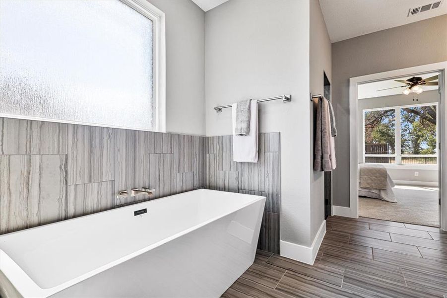 Bathroom featuring ceiling fan, tile walls, a bathing tub, and tile patterned floors