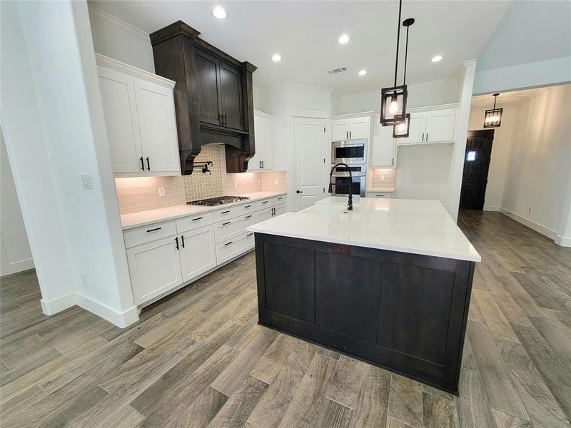 Kitchen featuring white cabinets, stainless steel appliances, and a kitchen island with sink