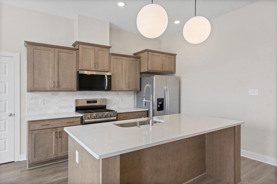 Kitchen featuring wood-finish cabinetry, stainless steel appliances, white countertops, and a tile backsplash