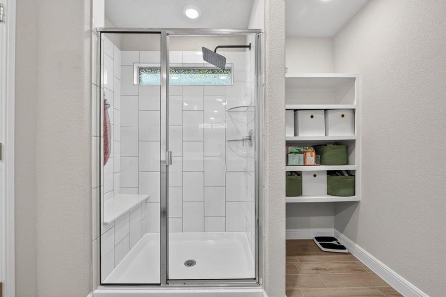 Walk-in shower with clear glass enclosure, white subway tile surround, built-in bench, and rain shower head