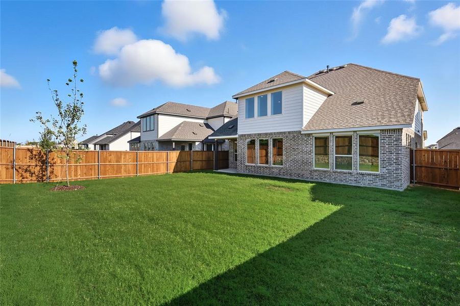 Rear view of property with brick siding, roof with shingles, and a fenced backyard Rear view of property with brick siding, roof with shingles, and a fenced backyard