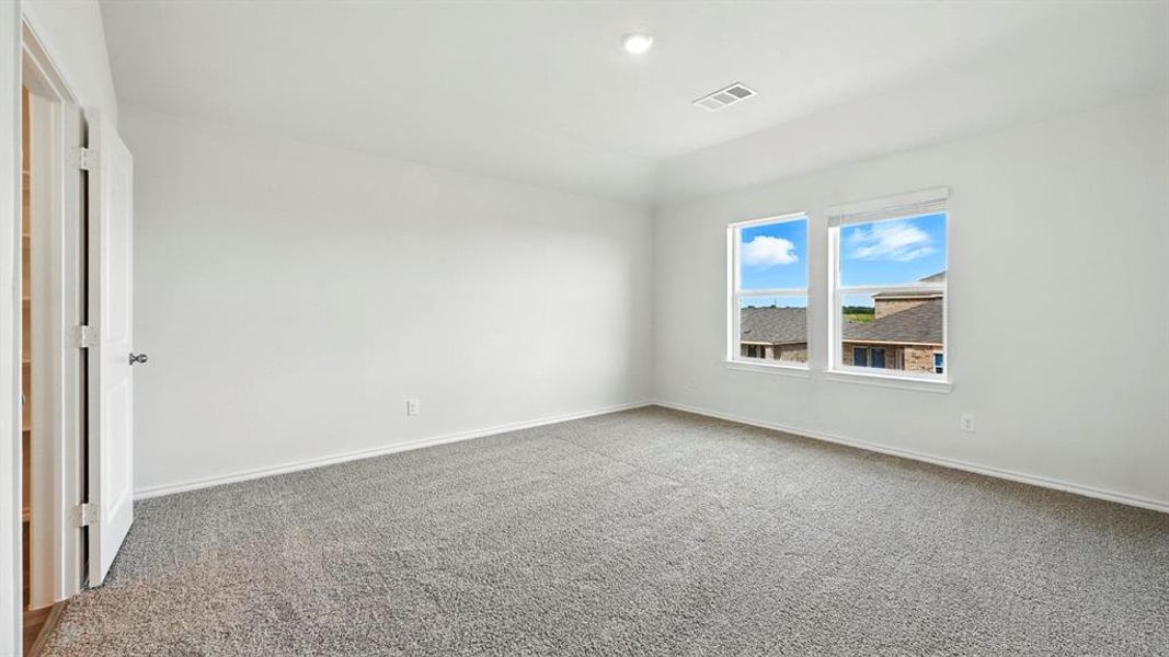 Bright room featuring two large windows, neutral gray carpeting, white walls, and a white ceiling with a recessed light fixture