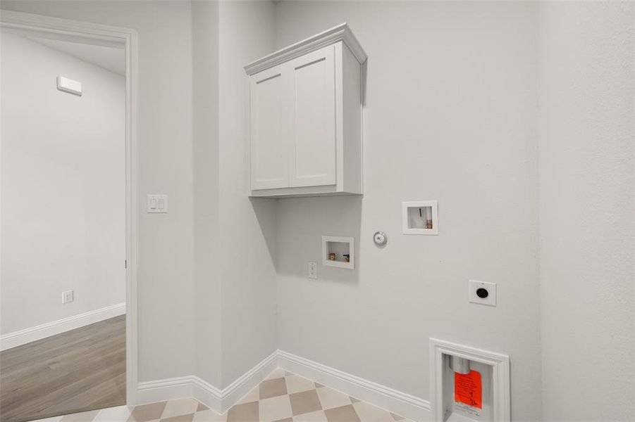 Washroom featuring hookup for an electric dryer, tile patterned floors, washer hookup, cabinet space, and hookup for a gas dryer Washroom featuring hookup for an electric dryer, tile patterned floors, washer hookup, cabinet space, and hookup for a gas dryer