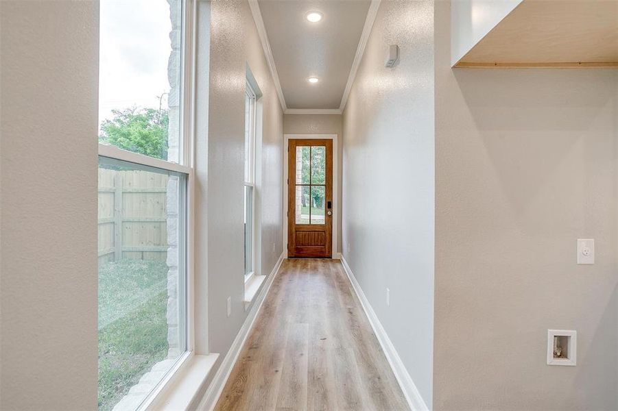 Doorway featuring crown molding, baseboards, and light wood-style flooring Doorway featuring crown molding, baseboards, and light wood-style flooring