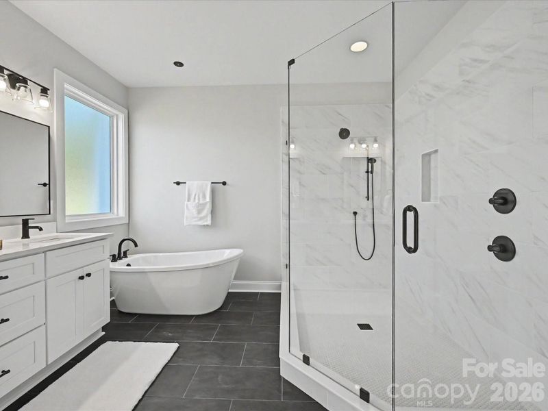 Luxurious primary bath features dual vanities, a freestanding soaking tub, and an oversized tiled walk-in shower with sleek modern finishes.
