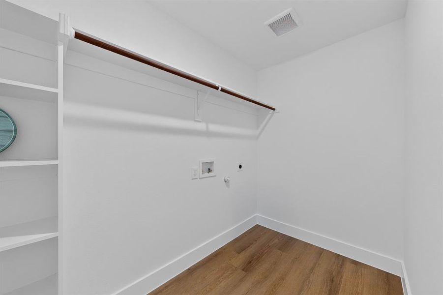 Dedicated laundry area featuring white walls, wood-finish flooring, and white baseboards