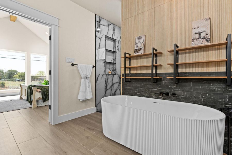 Full bath with a freestanding bath, vaulted ceiling, and wood finished floors Full bath with a freestanding bath, vaulted ceiling, and wood finished floors