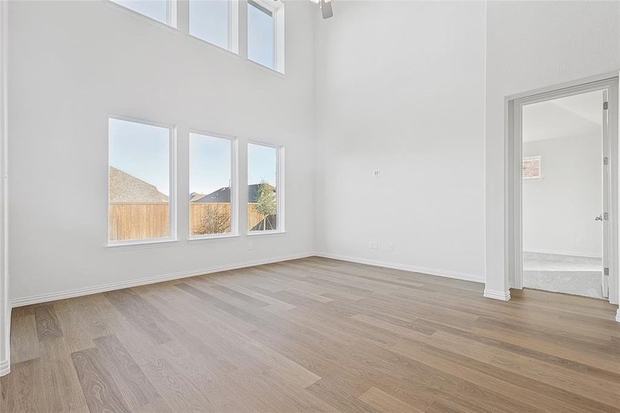 Unfurnished living room with light wood-type flooring and a high ceiling