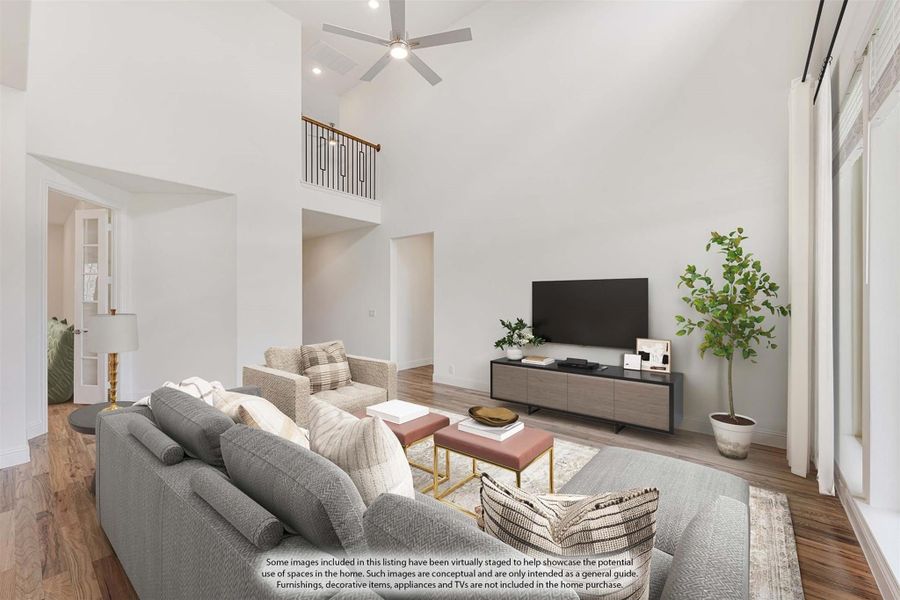 Living room with two-story ceiling, ceiling fan, hardwood floors, and second-floor balcony overlook Living room with two-story ceiling, ceiling fan, hardwood floors, and second-floor balcony overlook