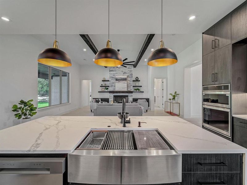 Kitchen featuring dishwasher, stainless steel double oven, open floor plan, a large fireplace, and recessed lighting